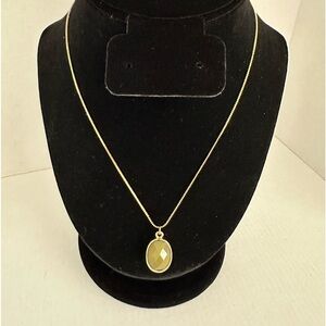 Green stone wrapped in gold tone metal with gold tone necklace